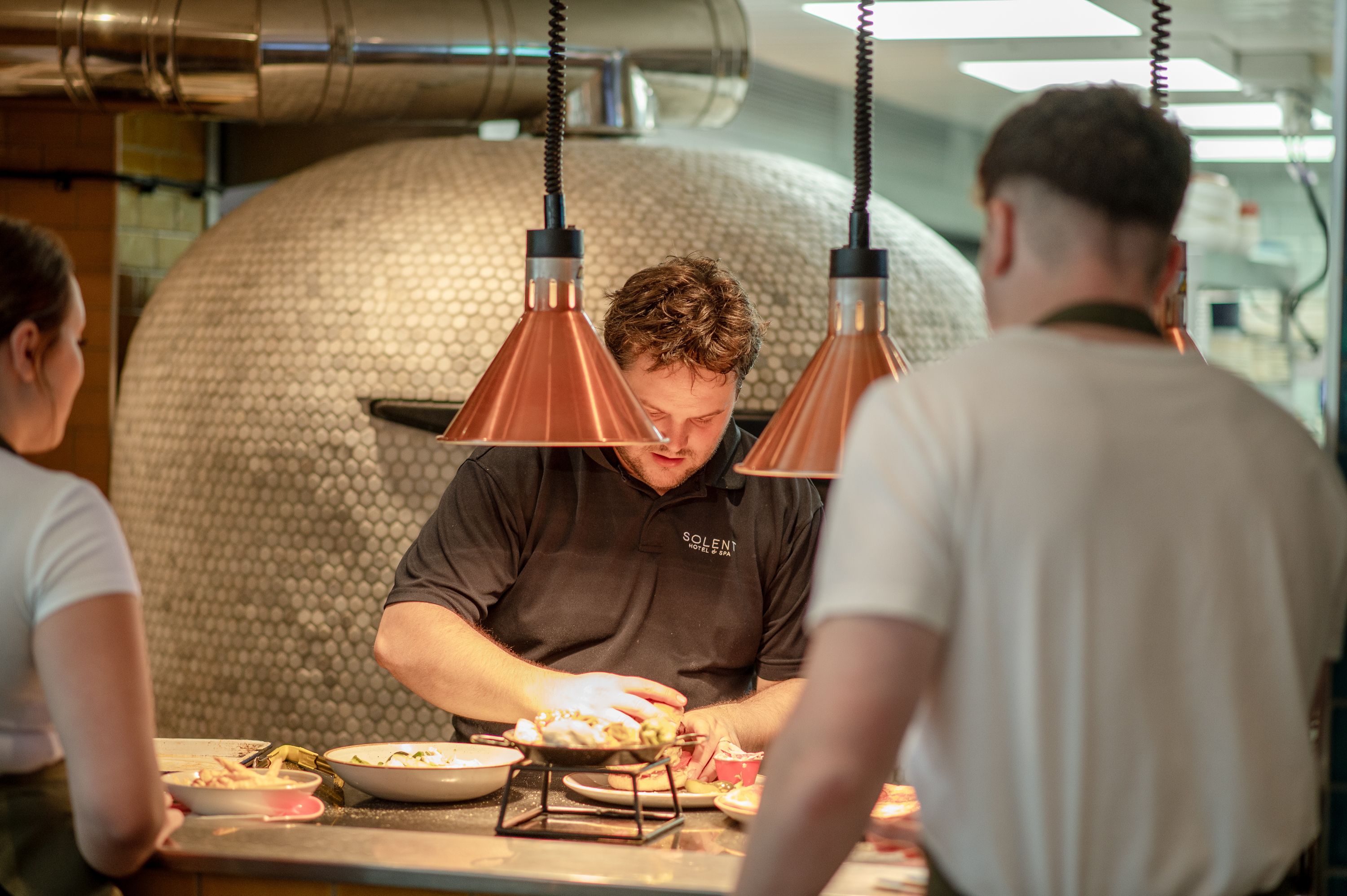 Chef plating up food with waiter waiting to serve food