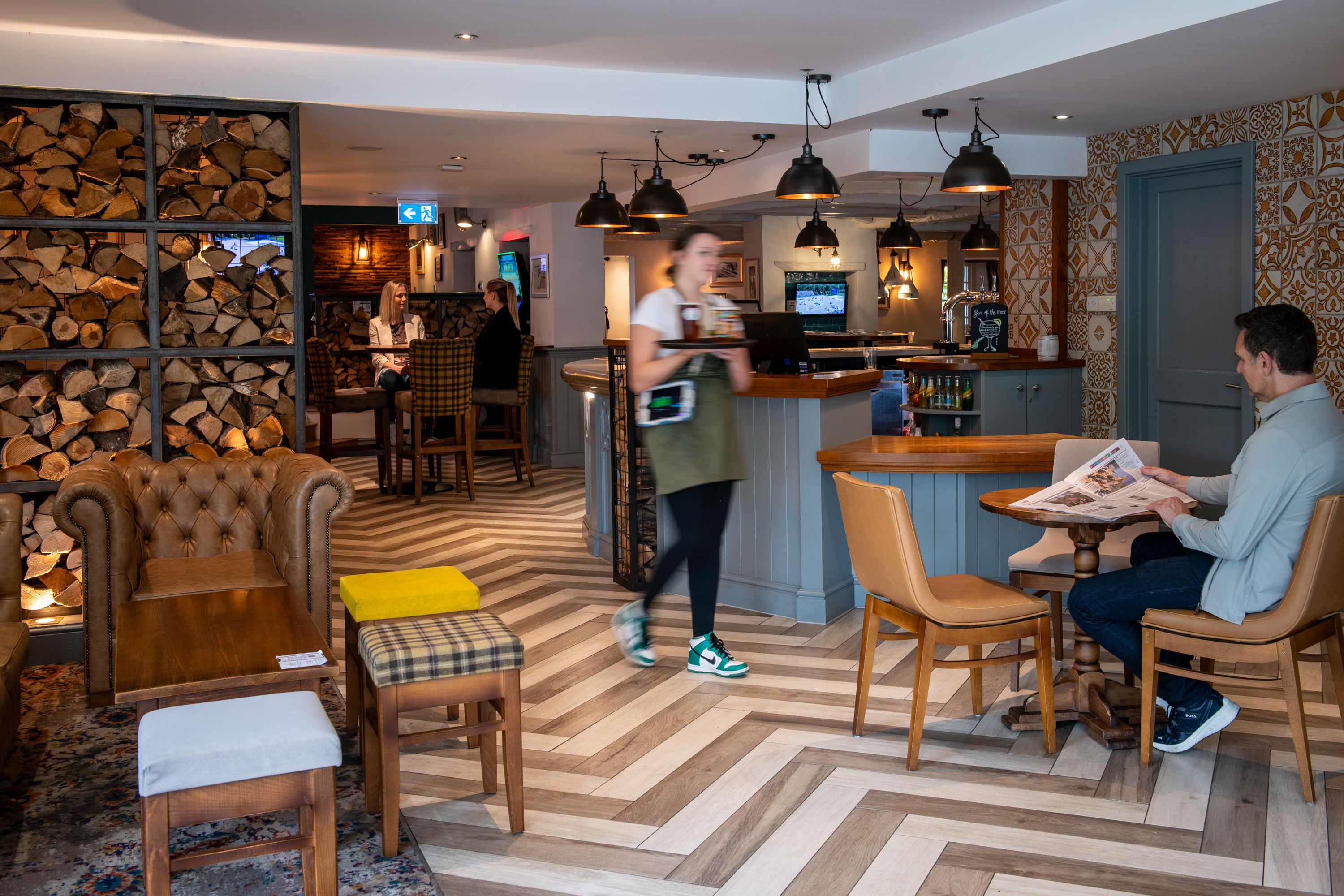 Women serving drinks to guy reading the newspaper