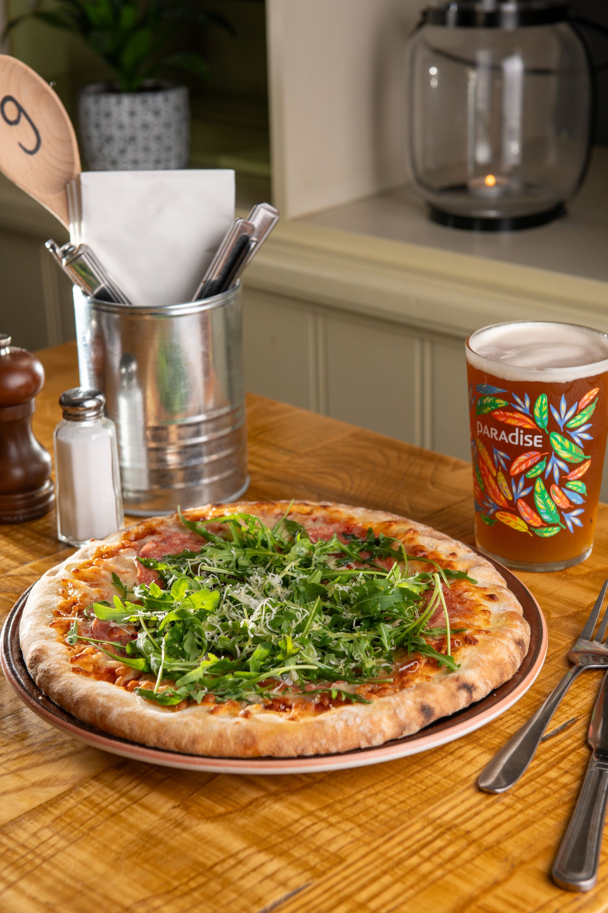 pizza with arugula and a pint of beer