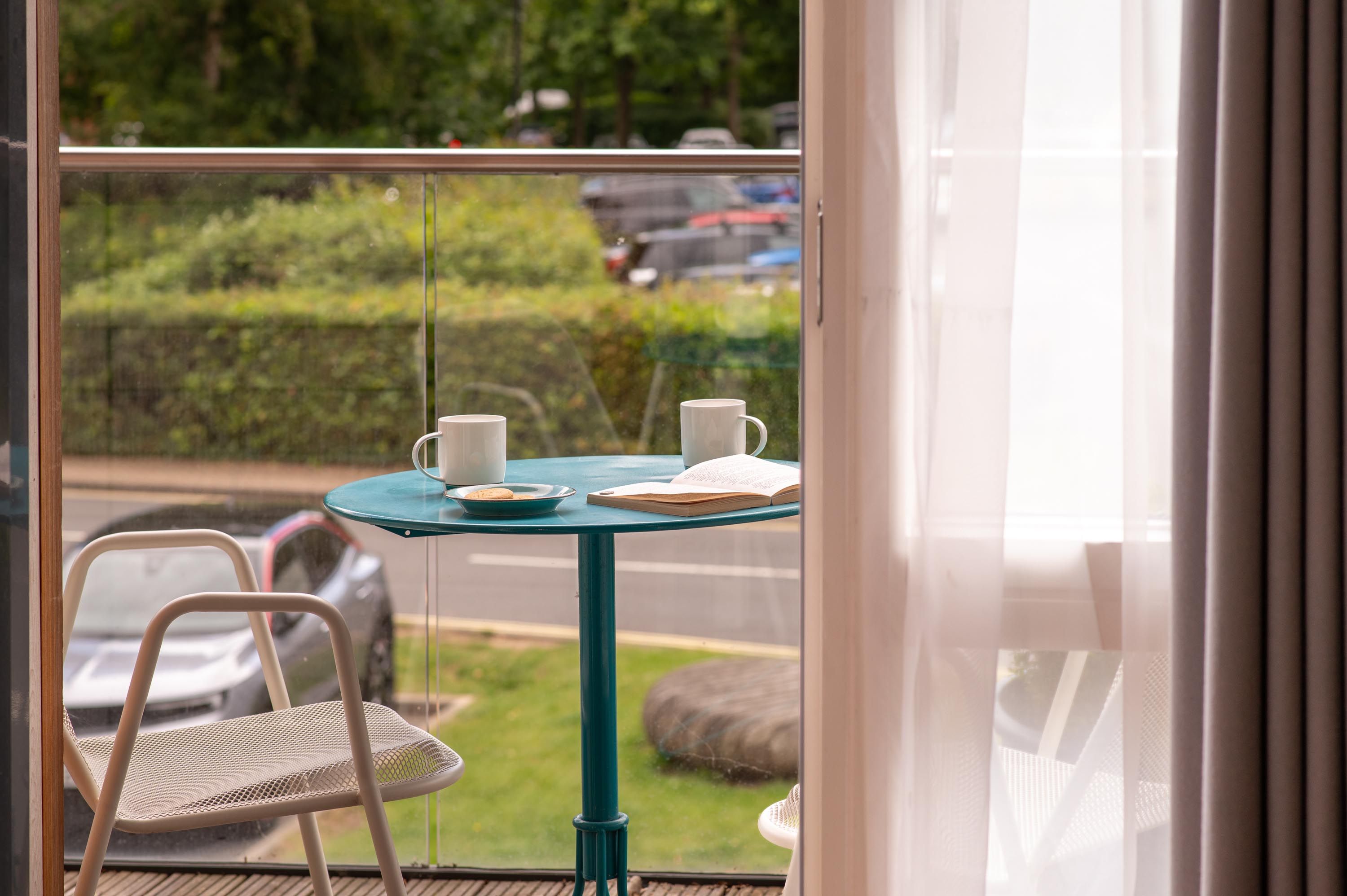 Close up of balcony with blue table and chairs with coffee cups on table