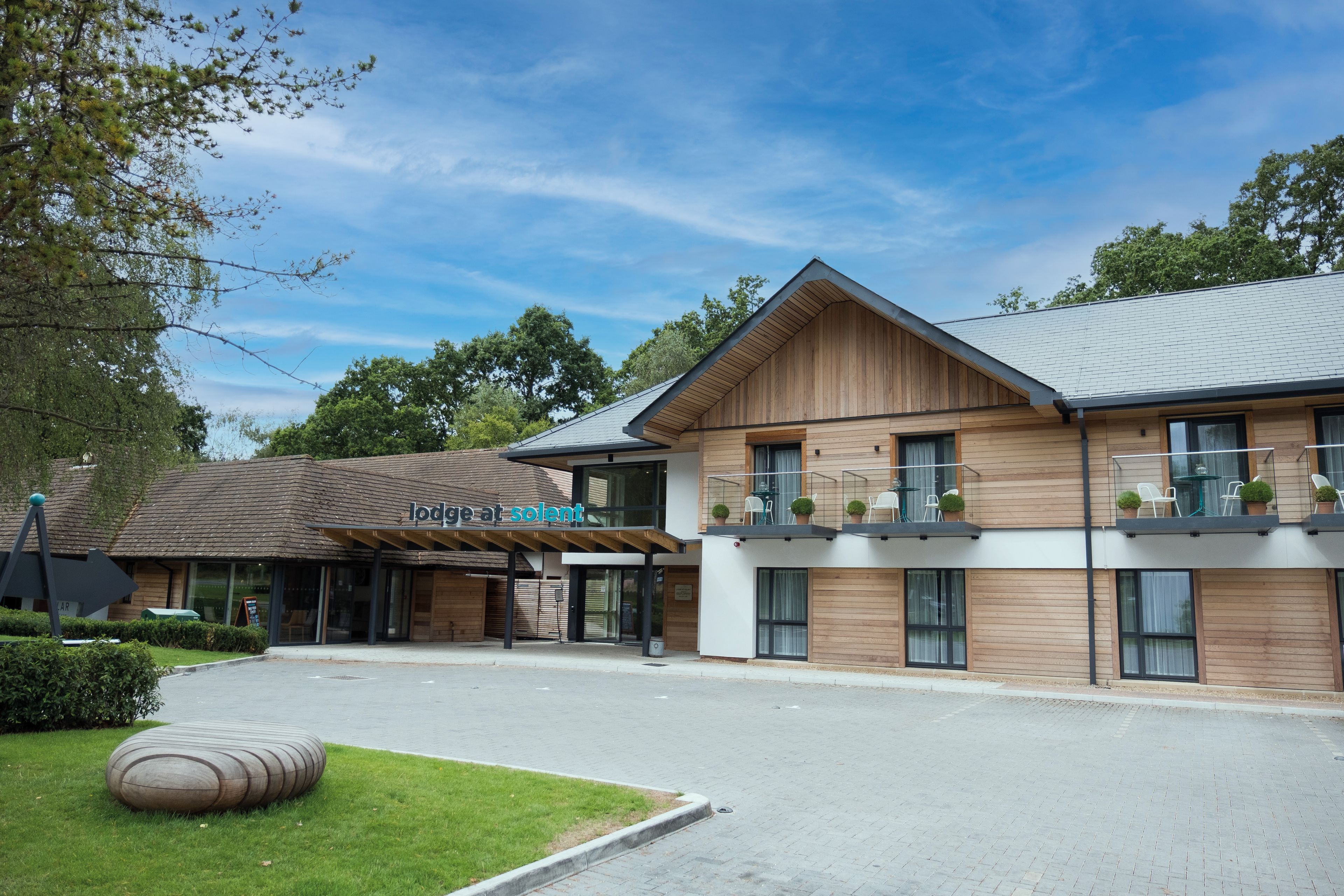 Exterior of Lodge at Solent with balcony rooms and Parson's Collar Pub with blue sky